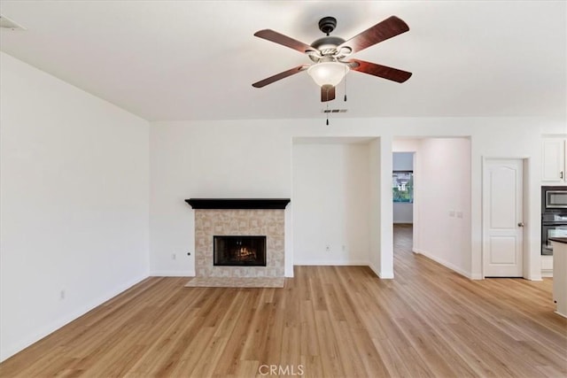 21567 Coral Rock Ln, Wildomar, CA 92595 - unfurnished living room with a ceiling fan, light wood-style floors, a fireplace, and baseboards