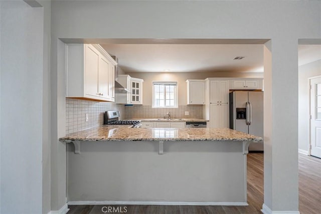 10113 Harvest Ave, Santa Fe Springs, CA 90670 - kitchen featuring stainless steel appliances, light stone countertops, a peninsula, decorative backsplash, and exhaust hood