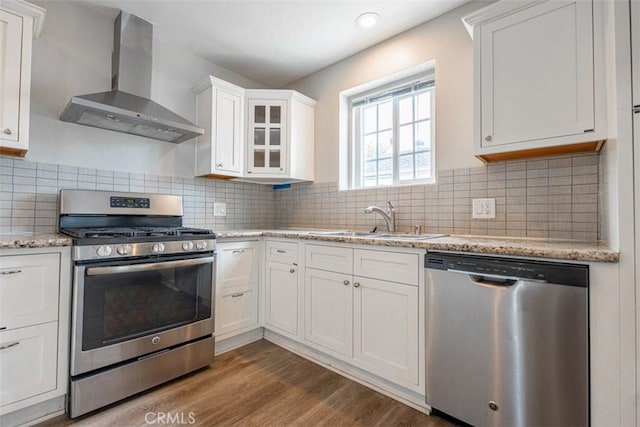 10113 Harvest Ave, Santa Fe Springs, CA 90670 - kitchen with appliances with stainless steel finishes, wall chimney exhaust hood, a sink, wood finished floors, and white cabinetry