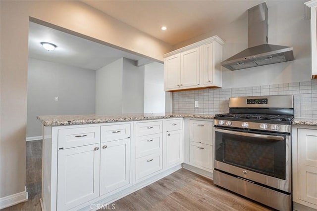 10113 Harvest Ave, Santa Fe Springs, CA 90670 - kitchen with stainless steel gas stove, wall chimney exhaust hood, a peninsula, and light wood-style flooring