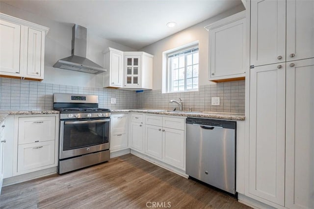 10113 Harvest Ave, Santa Fe Springs, CA 90670 - kitchen featuring wall chimney exhaust hood, appliances with stainless steel finishes, a sink, white cabinetry, and wood finished floors