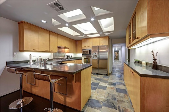 12841 Bloomfield St Unit 103, Studio City, CA 91604 - kitchen with stainless steel appliances, a peninsula, dark countertops, decorative backsplash, and a sink