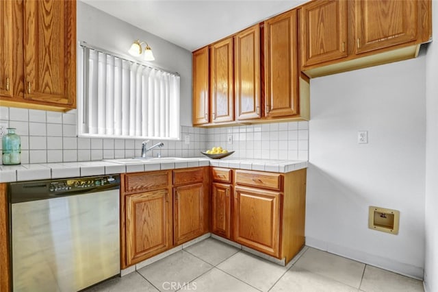27142 Langside Ave, Canyon Country, CA 91351 - kitchen with stainless steel dishwasher, a sink, brown cabinets, tasteful backsplash, and light tile patterned flooring