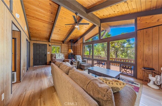 58632 Rainbow Dr, North Fork, CA 93643 - living area featuring a wood stove, wood walls, light wood-style floors, wooden ceiling, and ceiling fan