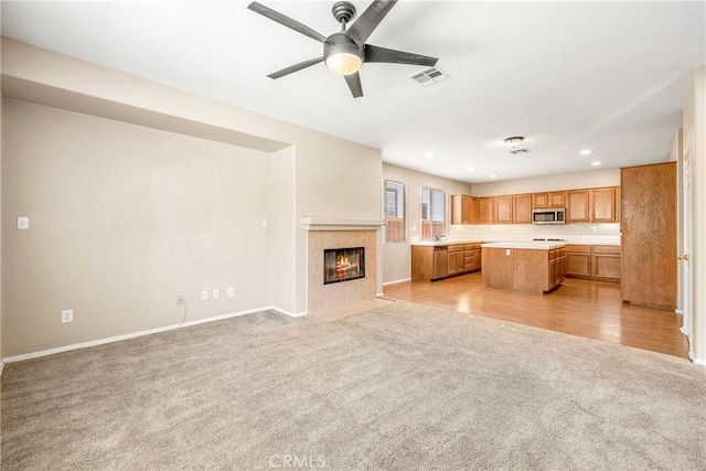 33010 Poppy St, Temecula, CA 92592 - kitchen with stainless steel microwave, light carpet, open floor plan, a center island, and light countertops