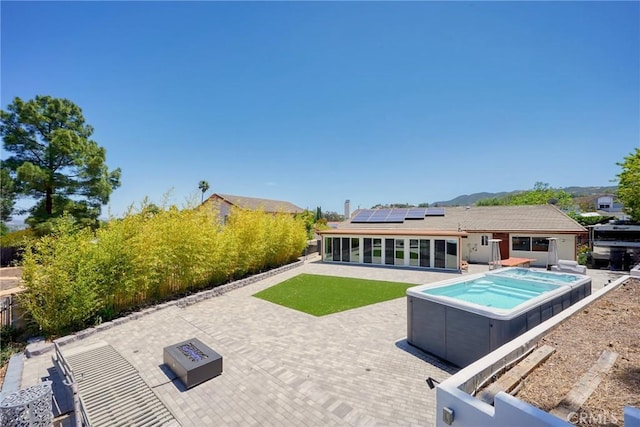 3076 Wauneta St, Newbury Park, CA 91320 - back of property with a hot tub, a patio, a sunroom, an outdoor fire pit, and solar panels