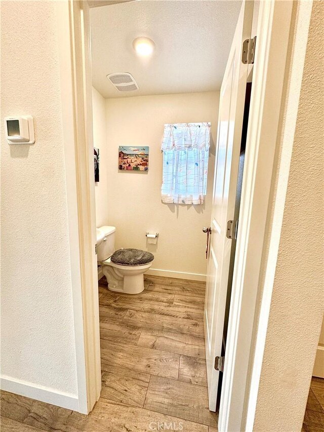 1147 Lentil Way, Chico, CA 95928 - bathroom with wood finished floors, toilet, baseboards, and a textured ceiling