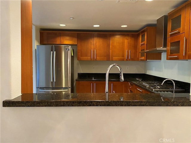 107 N Swall Dr Unit 304, Los Angeles, CA 90048 - kitchen featuring freestanding refrigerator, wall chimney range hood, glass insert cabinets, dark stone counters, and recessed lighting