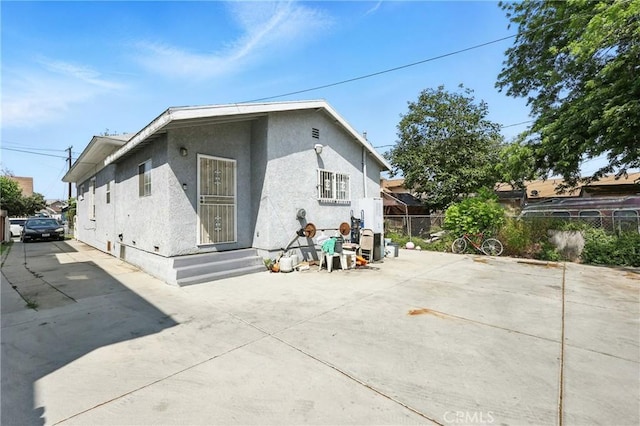 1600 E 33rd St, Los Angeles, CA 90011 - rear view of house featuring stucco siding, a patio, and driveway