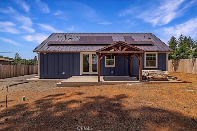 13654 Andover Dr, Magalia, CA 95954 - back of house with board and batten siding, a patio, roof mounted solar panels, and a fenced backyard