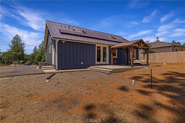 13654 Andover Dr, Magalia, CA 95954 - back of house featuring french doors, board and batten siding, a gazebo, roof mounted solar panels, and metal roof