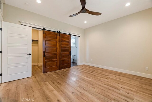 13654 Andover Dr, Magalia, CA 95954 - unfurnished bedroom featuring a barn door, baseboards, light wood-type flooring, recessed lighting, and a walk in closet