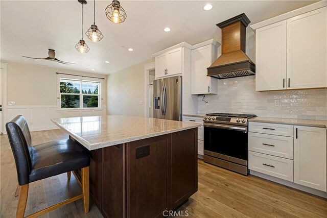 13654 Andover Dr, Magalia, CA 95954 - kitchen featuring stainless steel appliances, custom exhaust hood, wood finished floors, a kitchen island, and white cabinets