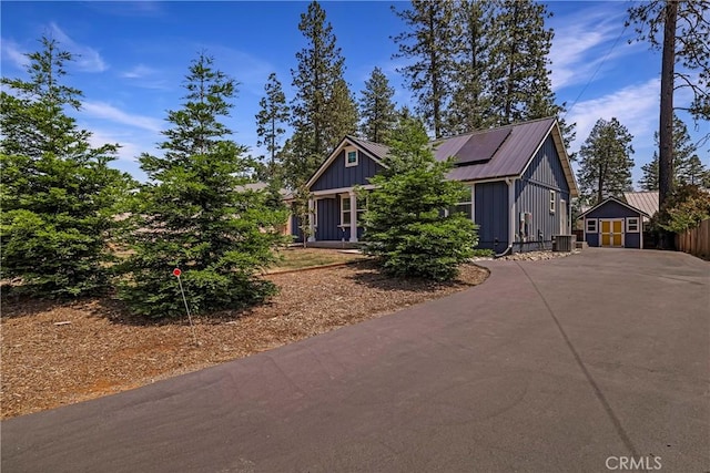 13654 Andover Dr, Magalia, CA 95954 - view of front of home with concrete driveway, roof mounted solar panels, central AC unit, board and batten siding, and metal roof