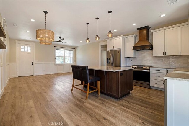 13654 Andover Dr, Magalia, CA 95954 - kitchen with appliances with stainless steel finishes, custom exhaust hood, light countertops, a kitchen island, and light wood finished floors