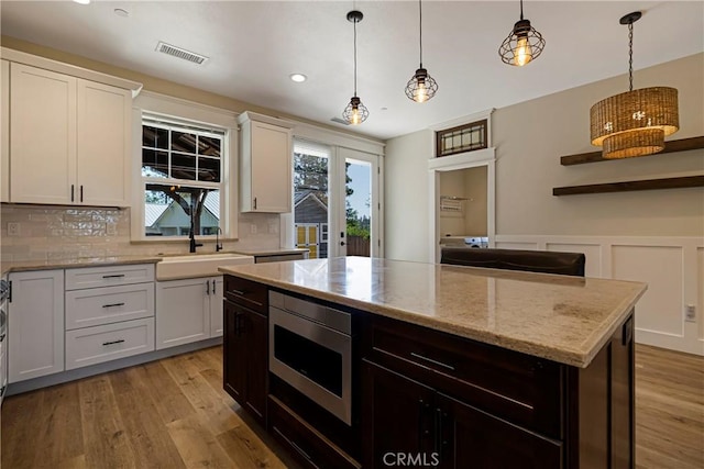 13654 Andover Dr, Magalia, CA 95954 - kitchen with stainless steel microwave, tasteful backsplash, a kitchen island, light wood-style flooring, and recessed lighting