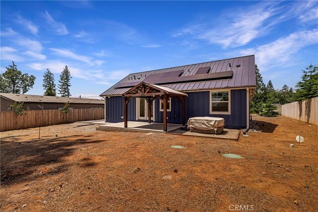 13654 Andover Dr, Magalia, CA 95954 - back of property featuring solar panels, a patio area, metal roof, a fenced backyard, and board and batten siding