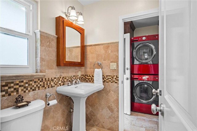 17652 Fiesta Way, Tustin, CA 92780 - bathroom featuring stacked washer and clothes dryer, tile walls, and healthy amount of natural light
