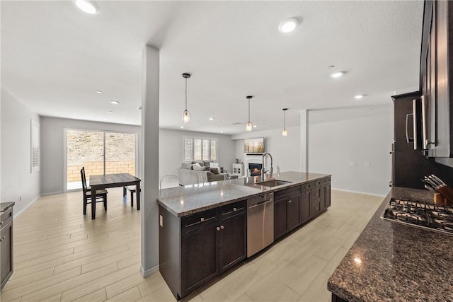 33168 Toledo Bend Ct, Winchester, CA 92596 - kitchen with stainless steel appliances, dark stone counters, a center island with sink, open floor plan, and light wood-style flooring
