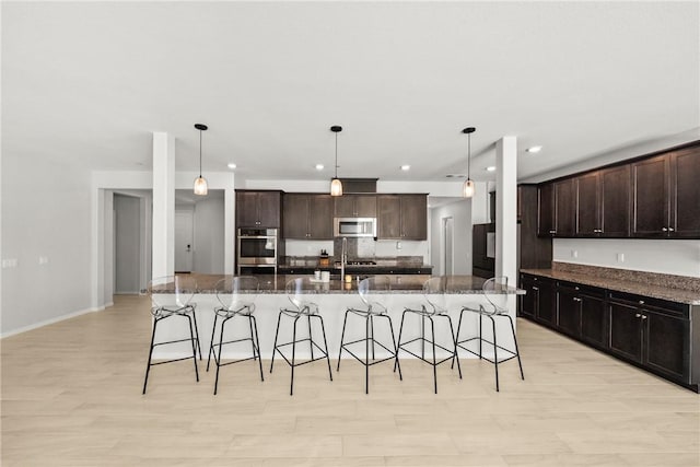 33168 Toledo Bend Ct, Winchester, CA 92596 - kitchen with stainless steel appliances, a breakfast bar, dark brown cabinets, a large island, and recessed lighting