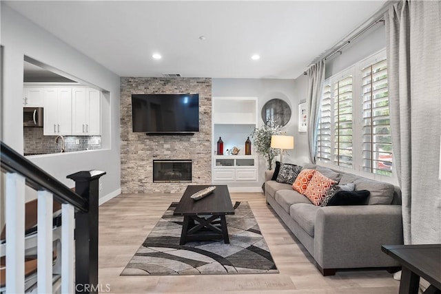 39 Windward Way, Buena Park, CA 90621 - living room with light wood-type flooring, a stone fireplace, recessed lighting, and built in shelves
