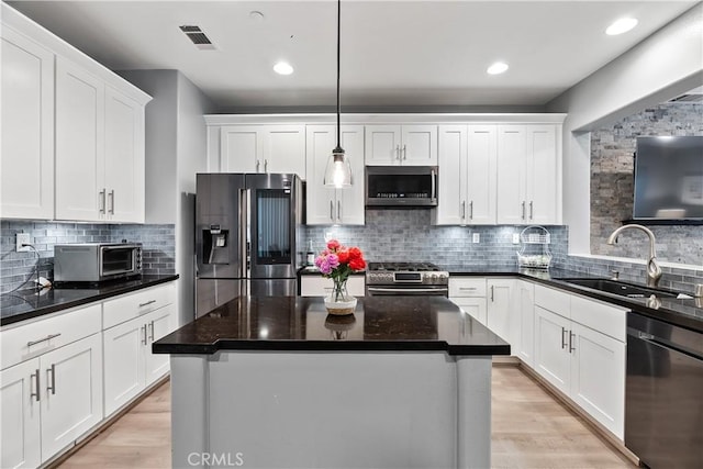 39 Windward Way, Buena Park, CA 90621 - kitchen with stainless steel appliances, white cabinets, light wood-style flooring, tasteful backsplash, and recessed lighting
