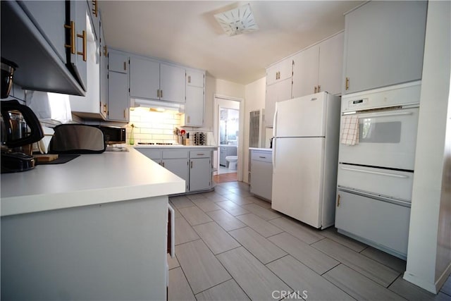 61740 Oleander Dr, Joshua Tree, CA 92252 - kitchen with white appliances, a warming drawer, backsplash, light countertops, and gray cabinetry