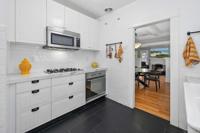 3818 Herbert St, San Diego, CA 92103 - kitchen with oven, stainless steel microwave, white cabinets, tasteful backsplash, and beam ceiling