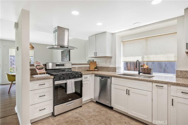 23326 Elfin Pl, Moreno Valley, CA 92557 - kitchen featuring appliances with stainless steel finishes, island range hood, white cabinetry, light stone countertops, and recessed lighting