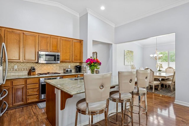 31920 Pasos Pl, Temecula, CA 92591 - kitchen featuring appliances with stainless steel finishes, brown cabinetry, dark wood-style flooring, backsplash, and crown molding