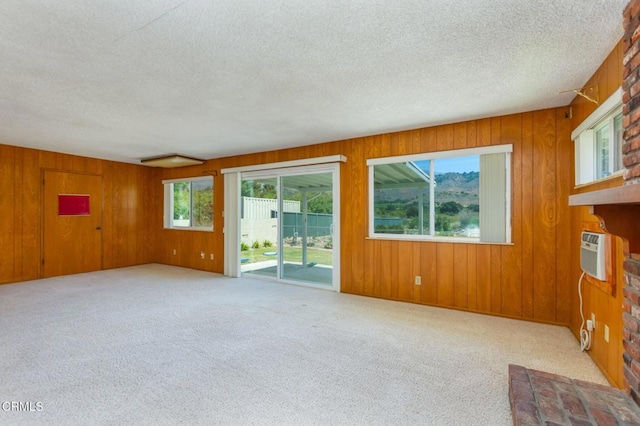 4190 Ojai Rd, Santa Paula, CA 93060 - carpeted empty room with plenty of natural light, a textured ceiling, a wall unit AC, wood walls, and a fireplace