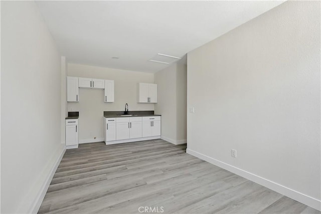 44242 Benald St, Lancaster, CA 93535 - kitchen with a sink, light wood finished floors, baseboards, white cabinets, and dark countertops