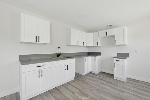 44242 Benald St, Lancaster, CA 93535 - kitchen featuring a sink, baseboards, light wood-type flooring, and white cabinetry