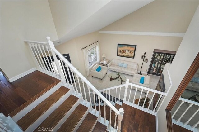 25009 Wintergreen Ct, Stevenson Ranch, CA 91381 - stairs featuring wood finished floors, baseboards, and high vaulted ceiling