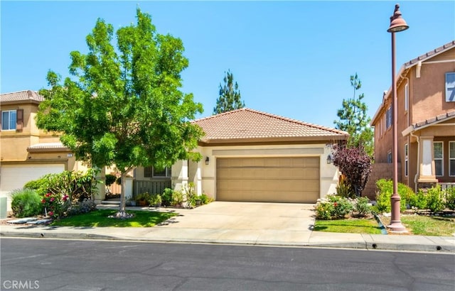 543 Garden Ave, Pomona, CA 91767 - view of front facade featuring a tiled roof, stucco siding, an attached garage, and concrete driveway