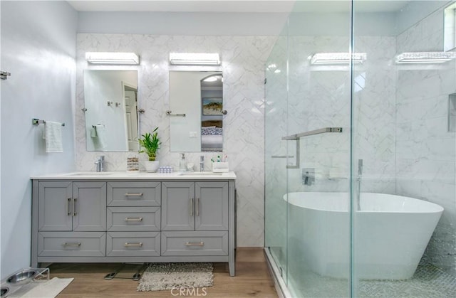 543 Garden Ave, Pomona, CA 91767 - bathroom with a soaking tub, wood finished floors, double vanity, a shower stall, and tile walls