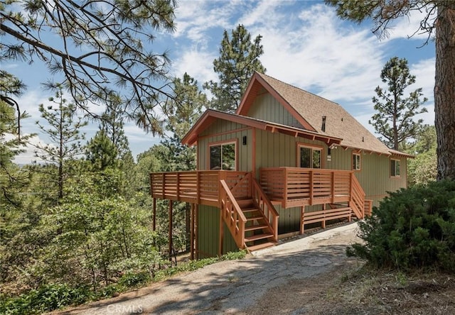 27947 St Bernard Ln, Lake Arrowhead, CA 92352 - view of front facade with roof with shingles, a wooden deck, and stairs