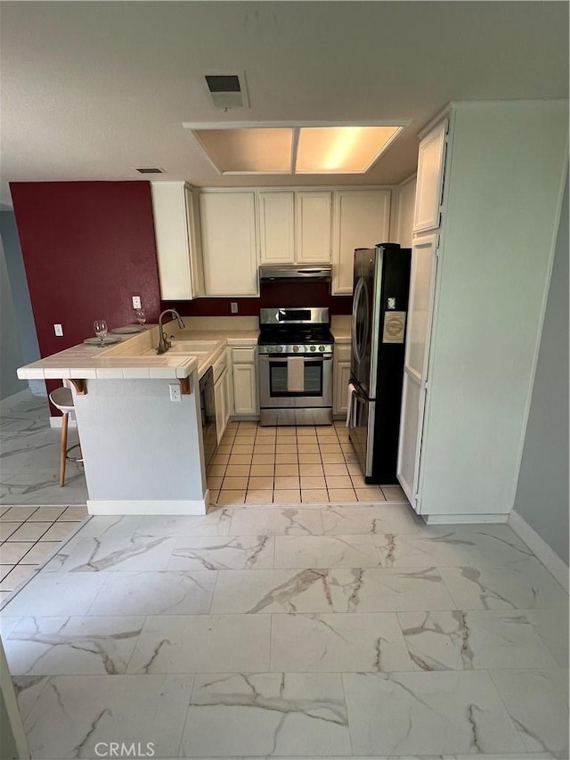 21212 Camelia Unit 46, Lake Forest, CA 92630 - kitchen featuring appliances with stainless steel finishes, under cabinet range hood, a sink, baseboards, and a peninsula