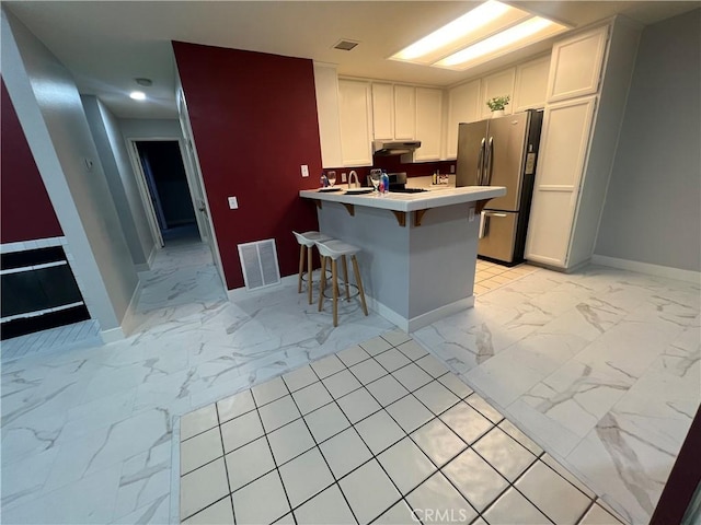 21212 Camelia Unit 46, Lake Forest, CA 92630 - kitchen featuring freestanding refrigerator, light marble finish floors, a peninsula, baseboards, and a kitchen bar