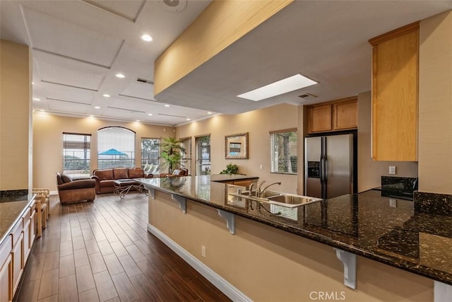 2400 San Gabriel Way Unit 205, Corona, CA 92882 - kitchen featuring stainless steel fridge, a sink, a peninsula, a breakfast bar, and dark stone countertops