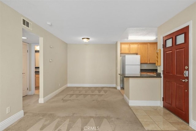 2400 San Gabriel Way Unit 205, Corona, CA 92882 - kitchen featuring dark countertops, baseboards, light carpet, a peninsula, and freestanding refrigerator