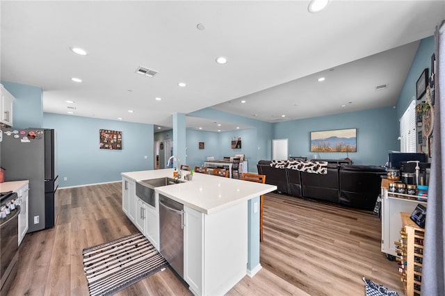 1372 Bello Pl, San Jacinto, CA 92582 - kitchen with appliances with stainless steel finishes, a sink, white cabinets, a center island with sink, and recessed lighting