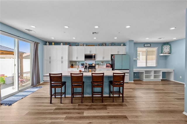 1372 Bello Pl, San Jacinto, CA 92582 - kitchen with stainless steel appliances, white cabinets, a center island with sink, recessed lighting, and light countertops