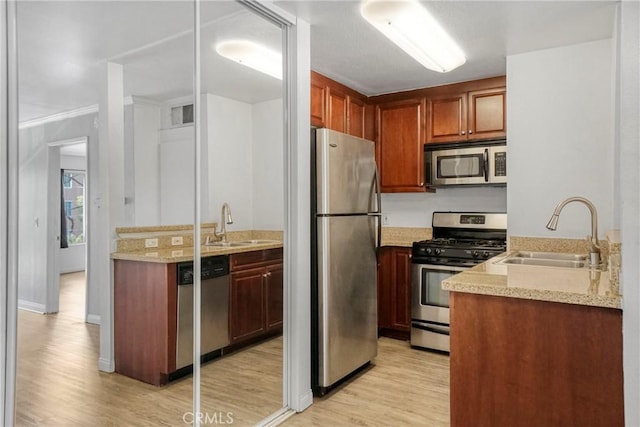 5500 Owensmouth Ave Unit 218, Woodland Hills, CA 91367 - kitchen featuring appliances with stainless steel finishes, a sink, light wood finished floors, and light stone counters