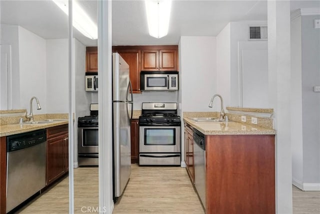 5500 Owensmouth Ave Unit 218, Woodland Hills, CA 91367 - kitchen featuring appliances with stainless steel finishes, a sink, light wood-type flooring, and light stone countertops