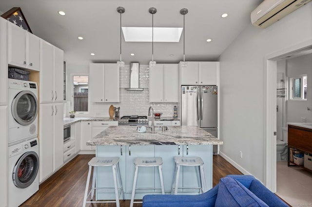 1918 S Freeman St, Oceanside, CA 92054 - kitchen with stainless steel appliances, wall chimney range hood, stacked washing machine and dryer, a wall mounted air conditioner, and backsplash