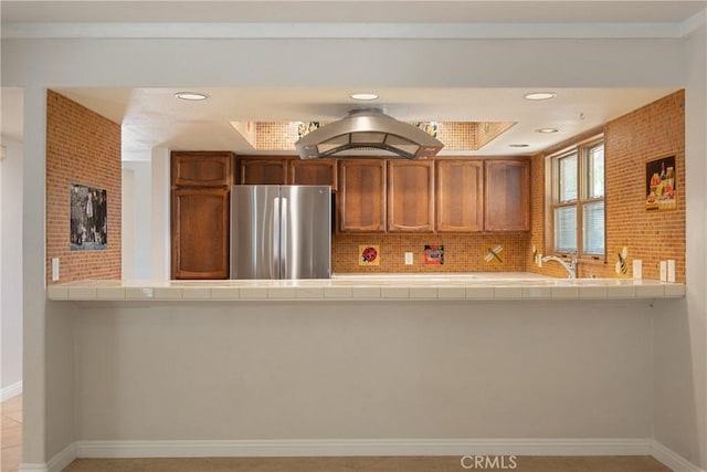 45740 Verba Santa Dr, Palm Desert, CA 92260 - kitchen featuring freestanding refrigerator, tile countertops, brown cabinets, a peninsula, and recessed lighting