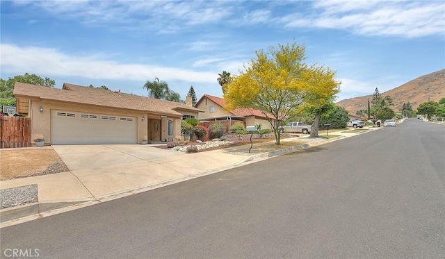 22784 Wren St, Grand Terrace, CA 92313 - view of front of house featuring a mountain view, stucco siding, an attached garage, and driveway