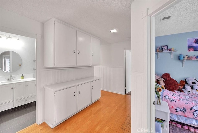 22784 Wren St, Grand Terrace, CA 92313 - corridor with a sink, a textured ceiling, light wood-style floors, and a wainscoted wall