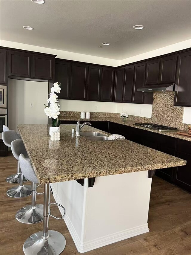7739 Lupin St, Chino, CA 91708 - kitchen featuring stainless steel appliances, stone counters, under cabinet range hood, a sink, and a kitchen breakfast bar
